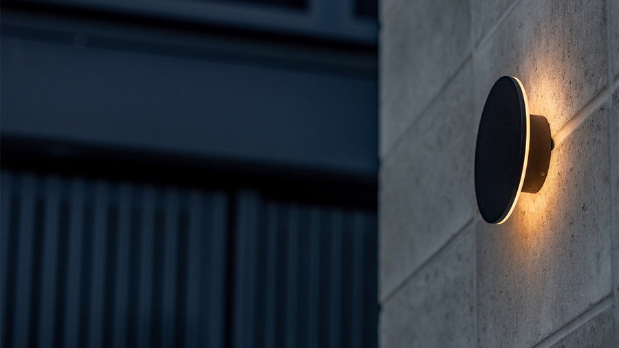 Havit Halo Round Black Wall Light Glowing on an Outdoor Rendered Block Wall at Dusk