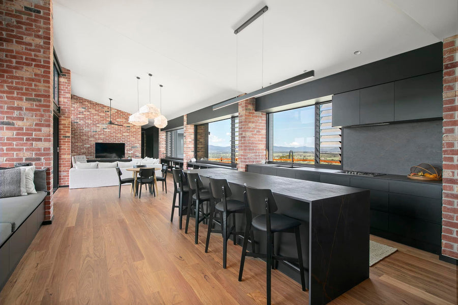 Black Linear Pendant Light Above Kitchen Island in Modern Brick Home